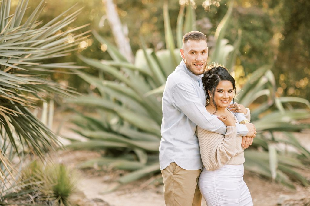 landscape portrait of engaged couple smiling at camera in the Arizona cactus garden